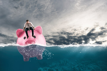 Business man in financial trouble sails on piggy bank in bad waters due to the crisis