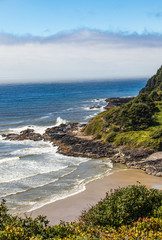 Wall Mural - Vertical Image - waves crashing on the rocky coast in Oregon with wall of fog offshore. 