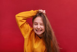 Fototapeta Tęcza - A broad smile of a girl in a sweater on a red background.