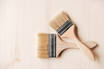 Two paint brushes with a wooden handle and natural bristles on a wooden background. Repair concept. Top view. Copy, empty space for text