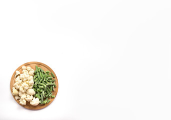 green beans, cauliflower blossoms on a wooden tray on a white background. healthy, dietary food. balanced nutrition