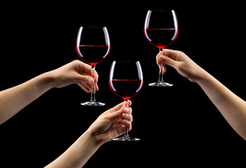 Set of hands holding red wine glass isolated on black.