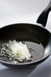 Chopped onion is being cooking on the black pan