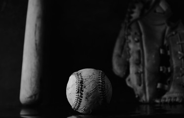Wall Mural - Dark baseball equipment background close up with vintage ball and glove in black and white.