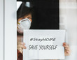 Woman standing at the window with a mask on her face and holding poster with the inscription: Stay at Home. Self-isolation is the only chance to stop the COVID-19.
Stay at home quarantine Coronavirus