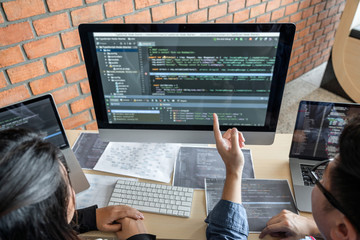 Leinwandbilder - Two professional programmer cooperating and working on web site project in a software developing on desktop computer at company, codes and typing data code, Programming with HTML, PHP and javascript