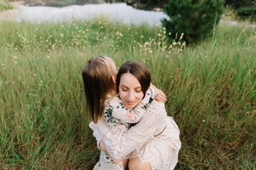 Mother with baby daughter, happy harmonious family outdoors, laughing and playing in the spring on the nature, in the mountains