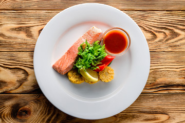 Wall Mural - salmon with salad and vegetables - dish on a wooden background