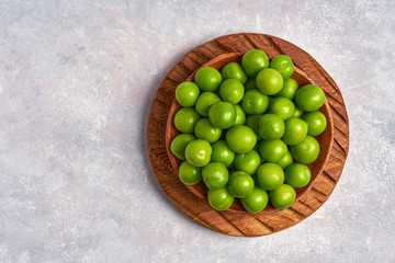 Wall Mural - Green sour plum in wooden bowl . Top view with copy space