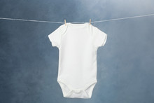 Child's Bodysuit Hanging On Laundry Line Against Dark Background