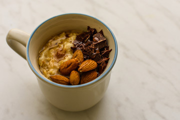 Oat porridge in cup for breakfast, on light colored table. Healthy eating, healthy food for breakfast