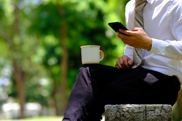 Poster - businessman using smartphone in the park and checking social networks, reading business news