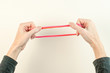 Red rubber band being stretched from two sides by woman.