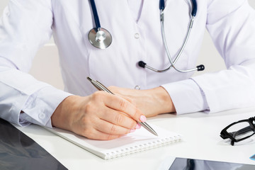 Close up female doctor hands writing on paper