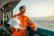 © Igor Kardasov - Filipino deck Officer on deck of vessel or ship , wearing PPE personal protective equipment - helmet, coverall, lifejacket, goggles. Safety and work at sea.