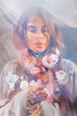 beautiful young woman with eyes closed  holding flowers at her neck under soft fabric