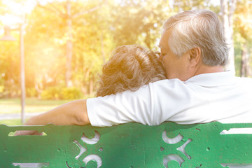 Wall Mural - Romantic senior couple. Grandfather embracing, kissing grandmother. Lovely elderly couple sitting on bench at park. Elderly man and old woman love each other so much. They alway stay together sunlight