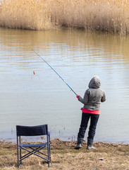 The girl catches fish in the lake for fishing rod.