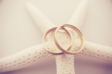 High Angle View Of Gold Wedding Rings On Artificial Starfish