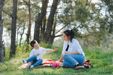 Happy young mother is playing with her baby in a park on a green lawn. Happiness and harmony of family life. Great family vacation. Good weekend. Mothers Day. Holiday. The concept of a happy family