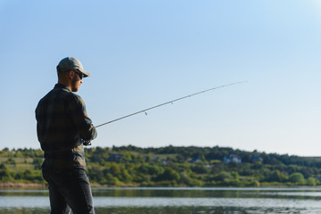 Wall Mural - A man catches a fish on a spinning fishing in the summer