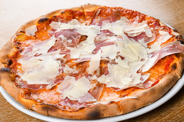 Italian pizza oven baked traditional with tomato sauce, mozzarella, prosciutto, arugula, parmesan