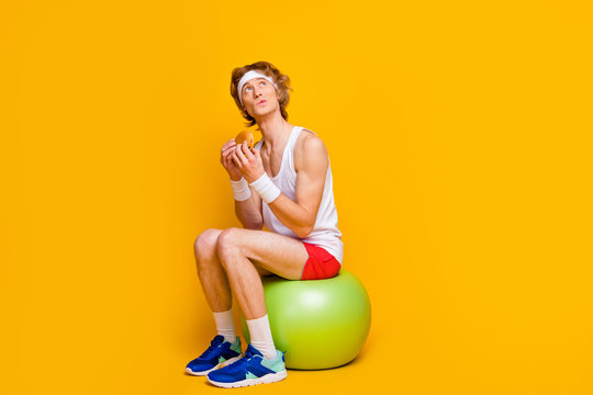 Portrait of his he nice attractive funky sportive guy sitting on fitball eating tasty yummy food counting calories isolated over bright vivid shine vibrant yellow color background