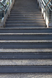 Fototapeta  - front view of outdoor staircase to pedestrian walkway with metal railing and glass fence at train station, selective focus.