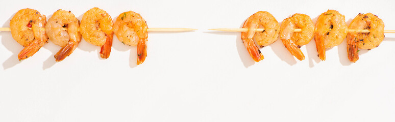 Wall Mural - top view of delicious fried prawns on skewers on white background, panoramic crop