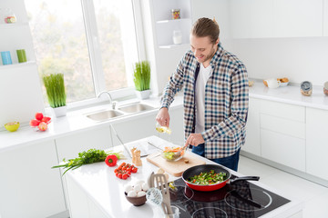 Photo of positive cheerful gourmet guy want cook tasty delicious salad for his wife pouring oil wear casual checkered plaid shirt in kitchen house indoors