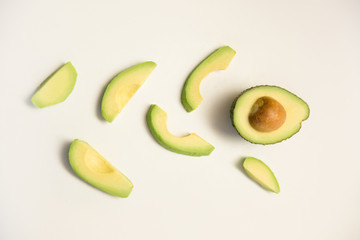 Slices and half of avocado fruit. Creative flat lay, top view. Isolated object on white background. Fresh food or healthy diet concept