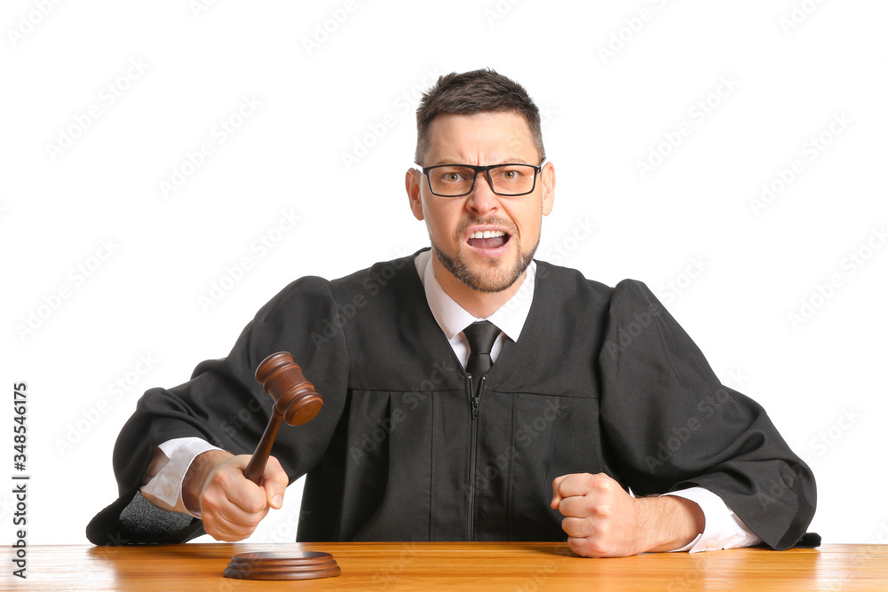 Angry male judge at table on white background