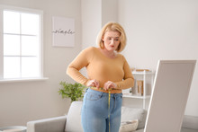 Sad Overweight Woman With Measuring Tape At Home. Weight Loss Concept