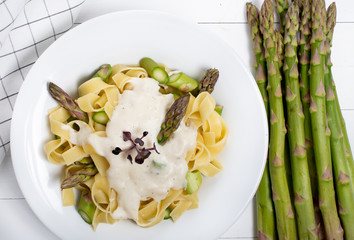 Wall Mural - Fresh homemade pasta dish of fettuccine or tagliatelle, green asparagus, white sauce, white plate