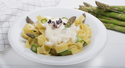 Wall Mural - Fresh homemade pasta dish of fettuccine or tagliatelle, green asparagus, white sauce, white plate