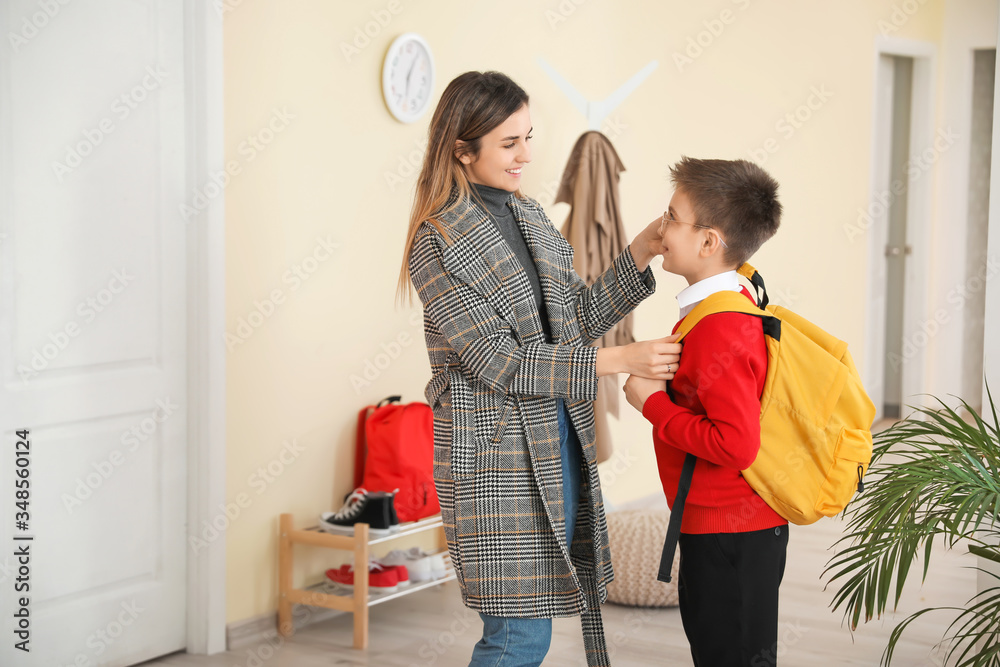 Cute schoolboy and his mother at home