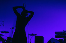 A Silhouette Of Singer Hip Hop Musician During Live Concert In Blue Light. Dark Background, Smoke, Spotlights