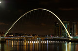 Illuminated Gateshead Millennium Bridge Over River At Night