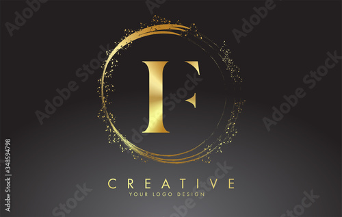 Fotografía F golden letter logo with golden sparkling rings and dust glitter on a black background