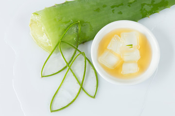 aloe vera leaves cut into thin slices, bowl with honey and pieces of aloe vera on white background