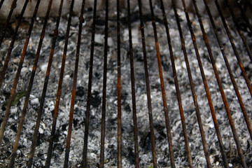 old rusty metal grill in front of ashes