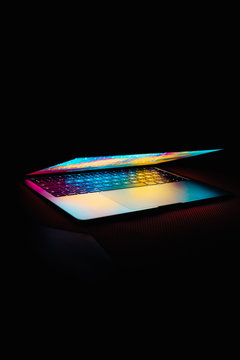 Modern laptop with colored lights on the screen that illuminate the keyboard