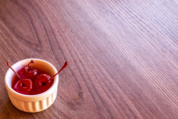 Delicious cherries in bowl on wooden background