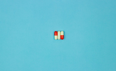 One white and two white-red capsules on a blue background. Three capsules. The concept of the pharmaceutical industry. Pharmacy. Disease Prevention