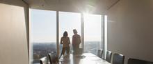 Business People Standing At Sunny Highrise Conference Room Window