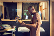 © Trevor Adeline/Caia Image - Happy male musician playing guitar in recording studio