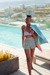 © Paul Bradbury/Caia Image - Confident, carefree young woman with towel at sunny poolside