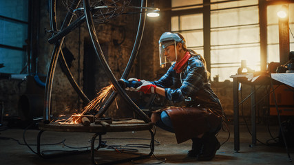 Young Contemporary Female Artist is Polishing a Metal Tube Sculpture with an Angle Grinder in a Studio Workshop. Pretty Empowering Woman.