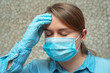 headache in a girl in a mask. symptom of the corona virus