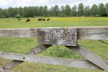 Sign Private On A Wooden Gate Around Green Field